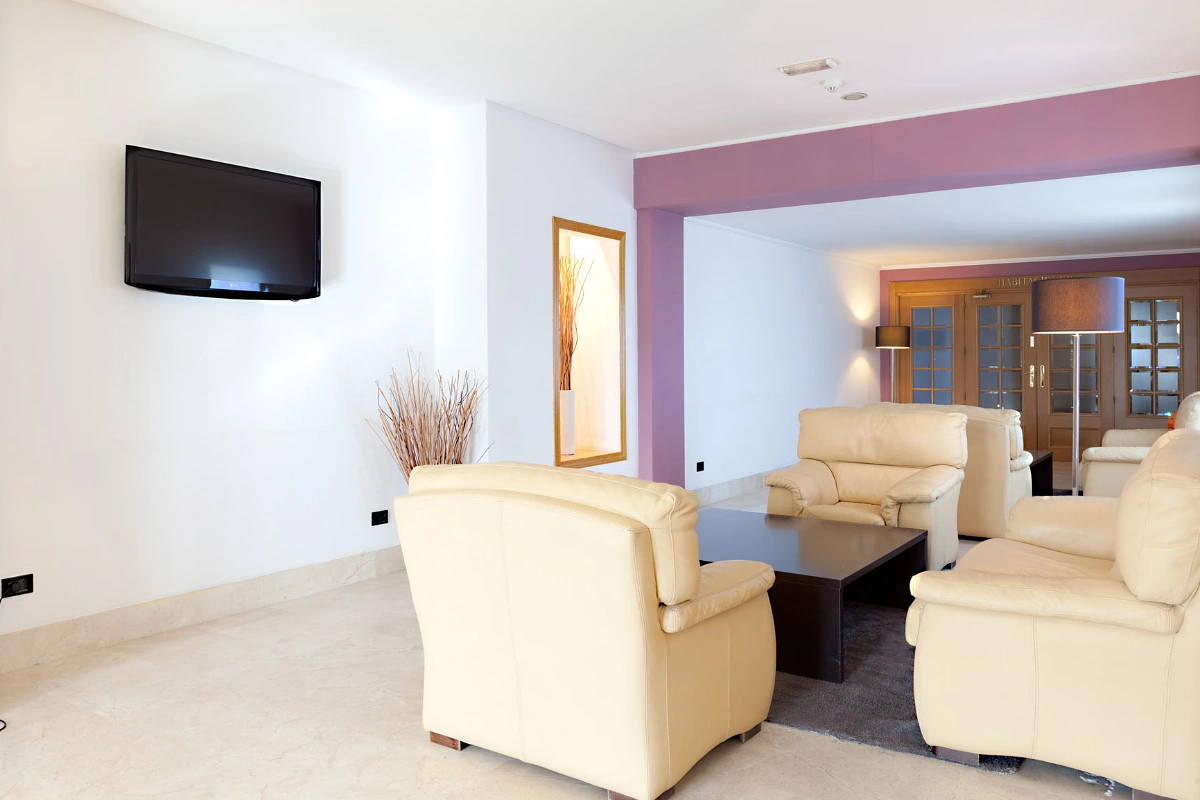Modern living room with beige sofas and television on white and violet wall