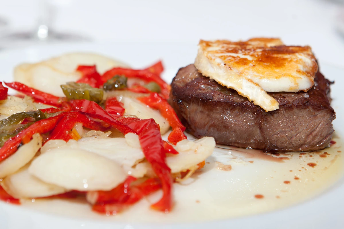 Steak with melted cheese and red and green pepper salad.