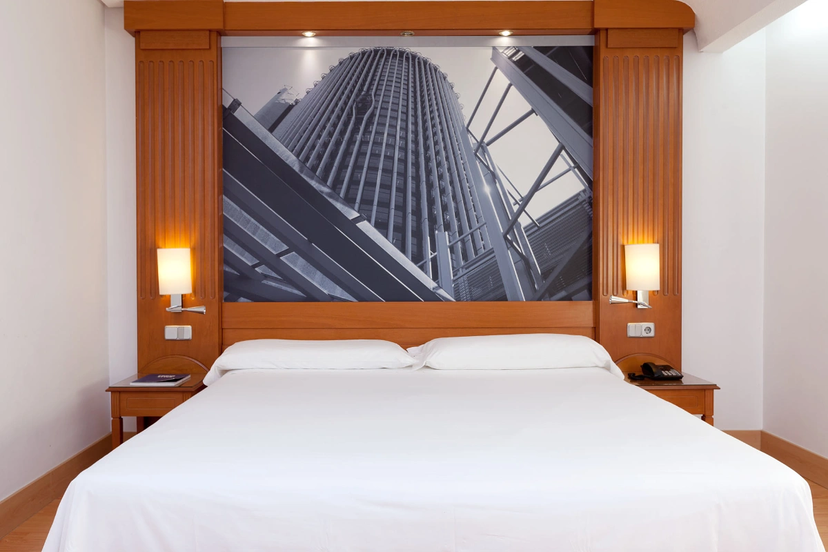 Hotel room with bed and mural of skyscrapers seen from below