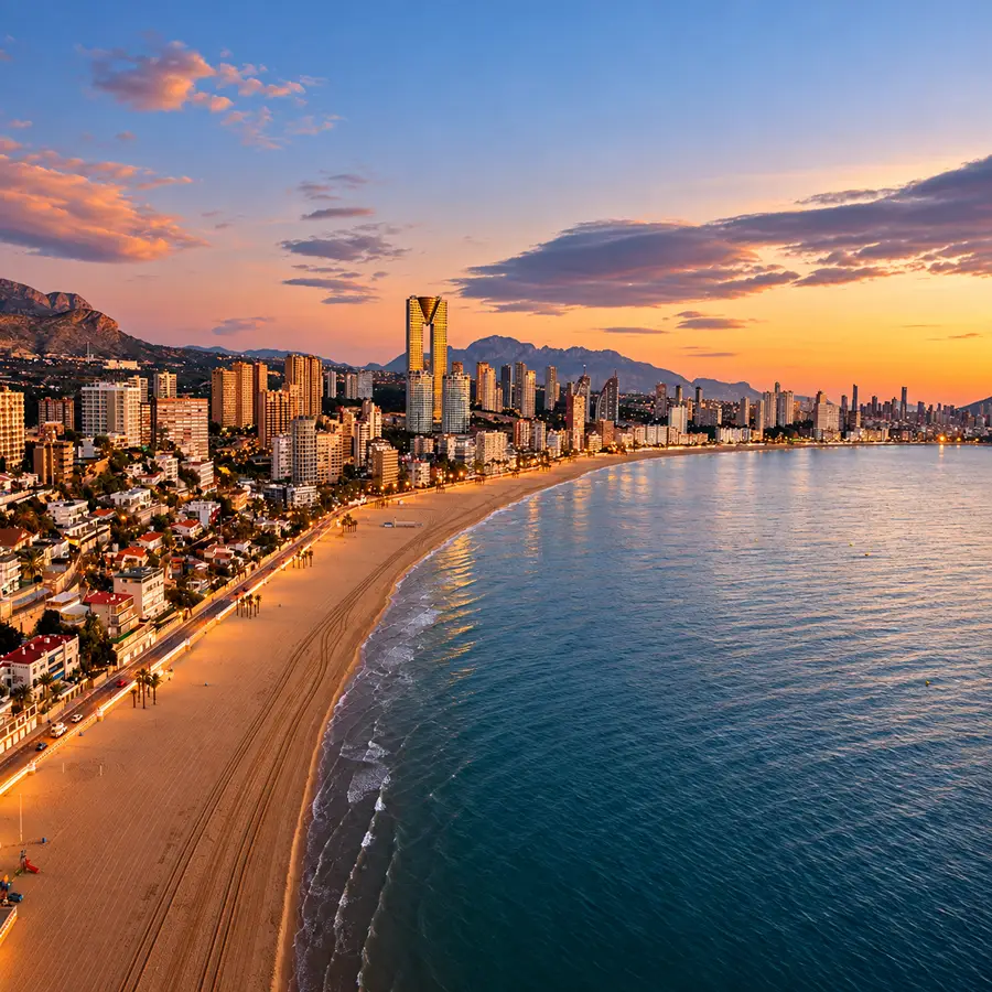 Amanecer en la costa con ciudad, rascacielos y playa junto al mar.