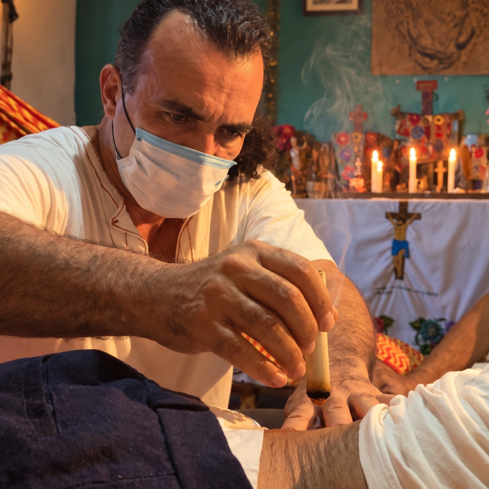 Hombre con mascarilla realiza un ritual de curaci&oacute;n, encendiendo una vela