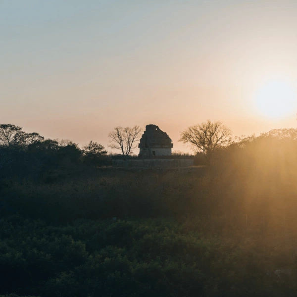 Sunset over an ancient monument in the forest, with rays of sunlight