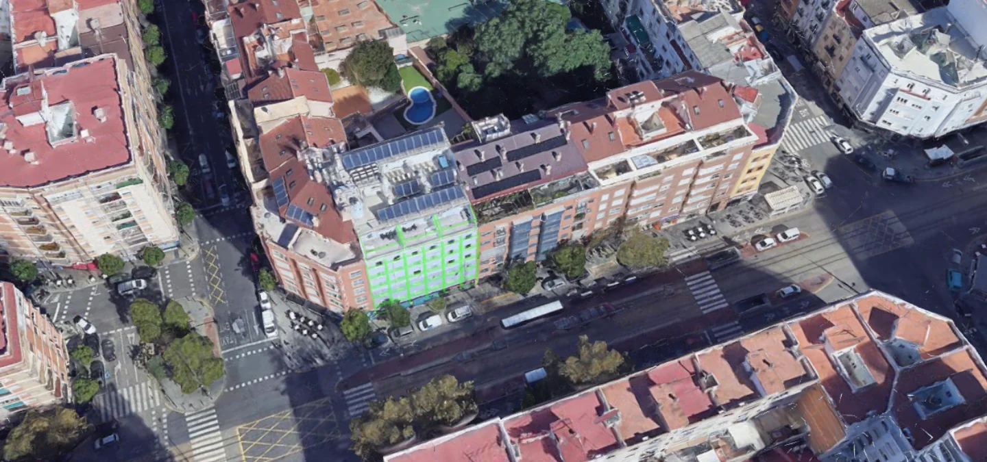 Vista aérea de un cruce de calles en una zona urbana con edificios y una piscina ovalada.