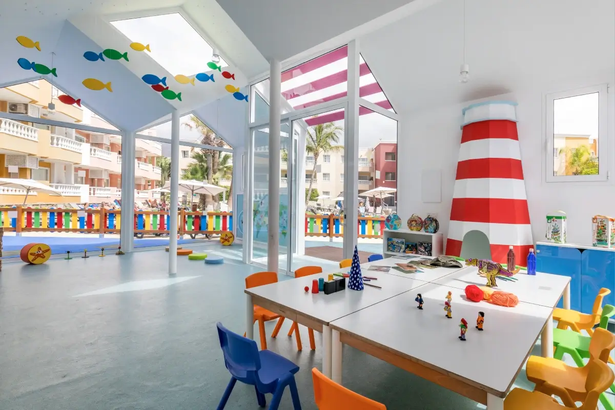 Aula infantil decorada con colores vivos, muebles de juegos y manualidades.