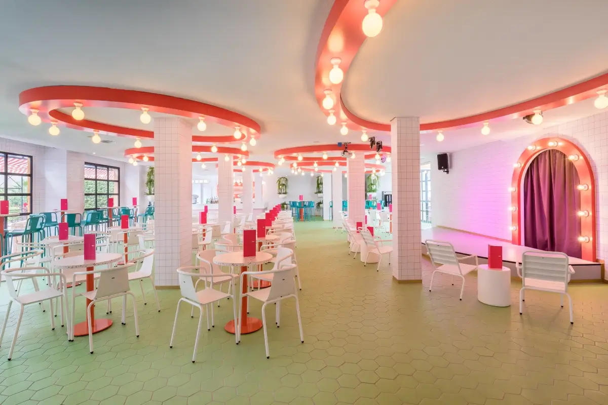 Interior moderno de una cafeter&iacute;a colorida, con sillas y mesas blancas.