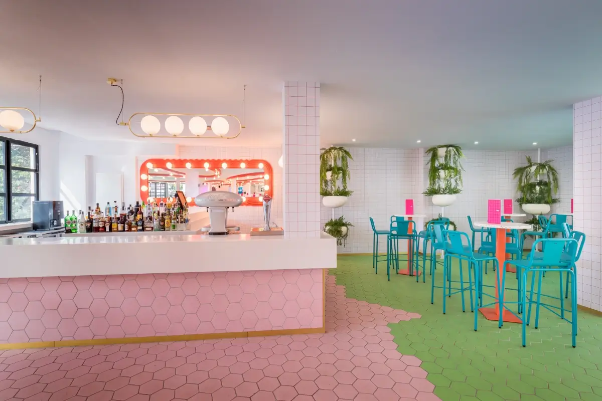 Bar moderno con decoraci&oacute;n colorida y sillas turquesas, ambiente retrofuturista.