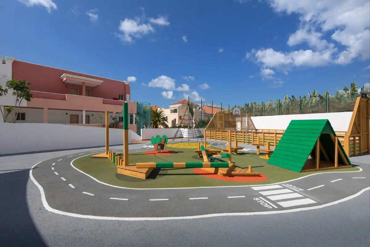 Patio de juegos con estructuras de madera y pista de circulaci&oacute;n.