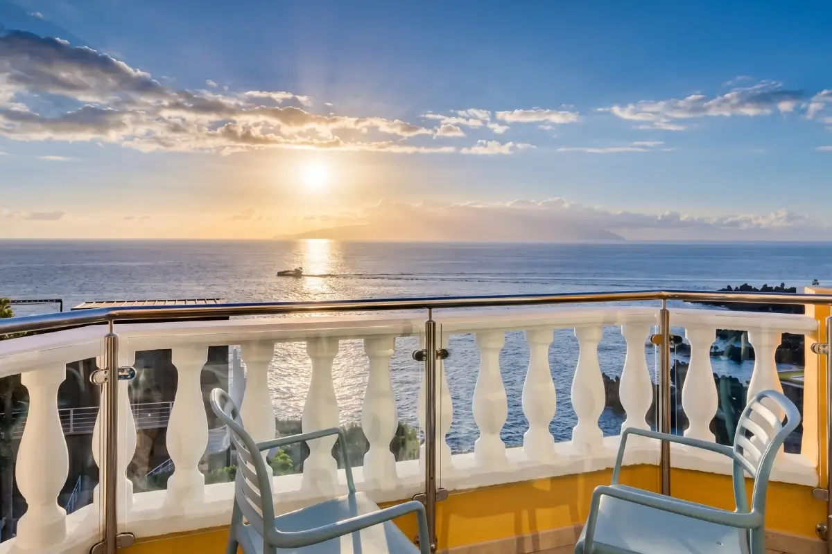 Terraza de barco frente al mar con sol y cielo nublado al atardecer