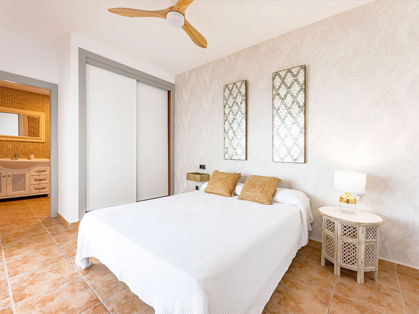 Habitación luminosa con cama, ventilador y baño integrado.