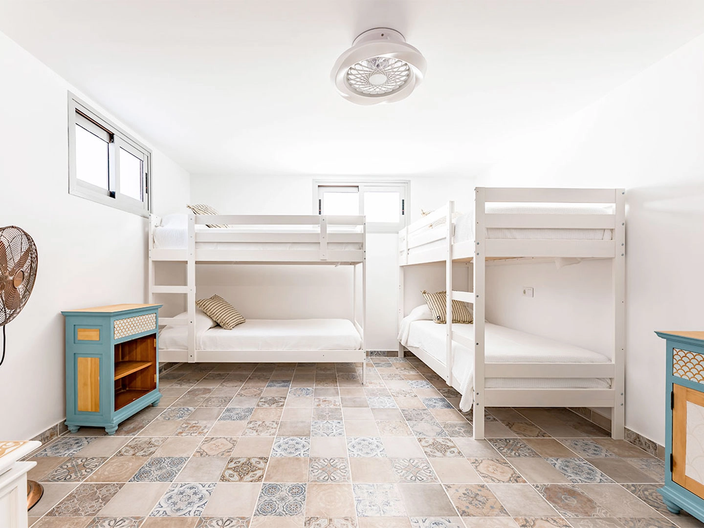 Litera blanca en habitación de azulejos y muebles azules.