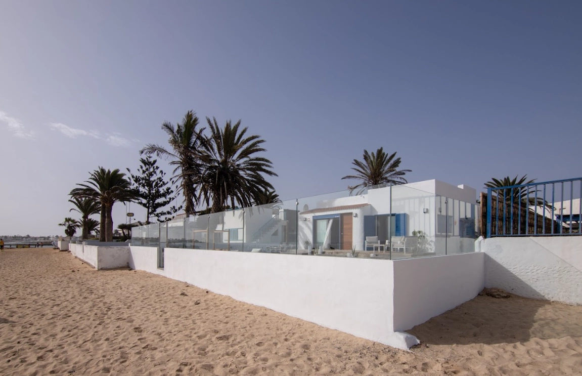 Casa blanca con palmeras en la playa, cerca del oc&eacute;ano.