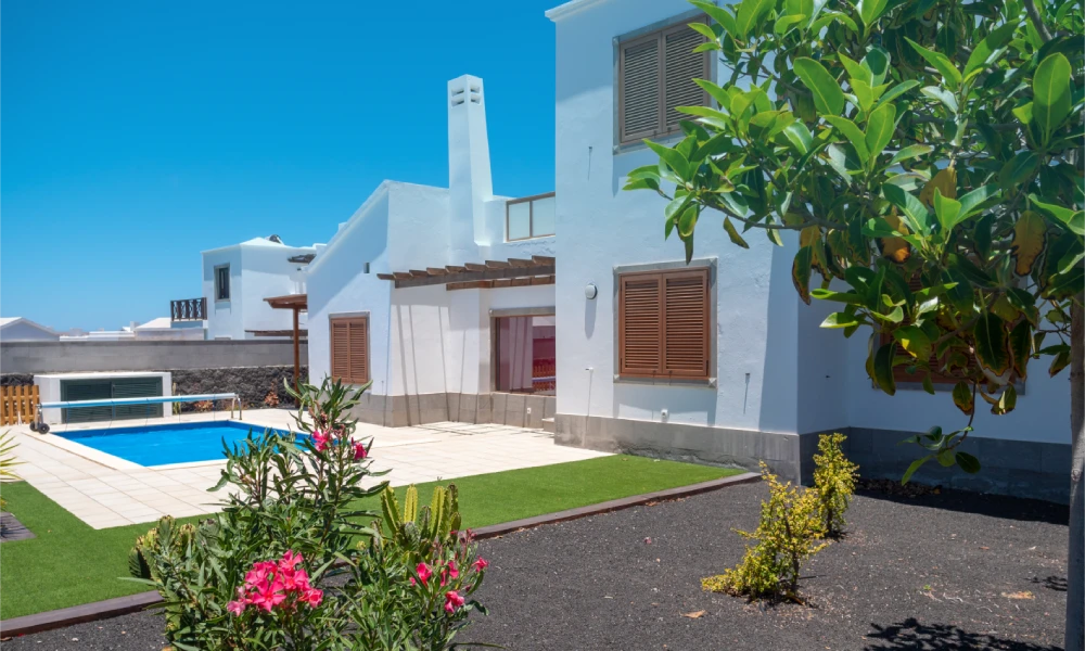 Casa blanca con piscina, jardín y cielo azul.