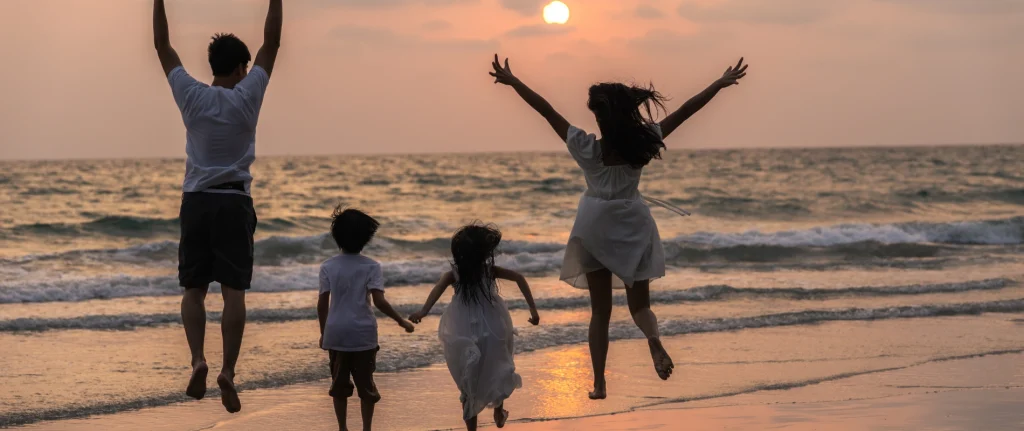 Familia saltando en la playa al atardecer.