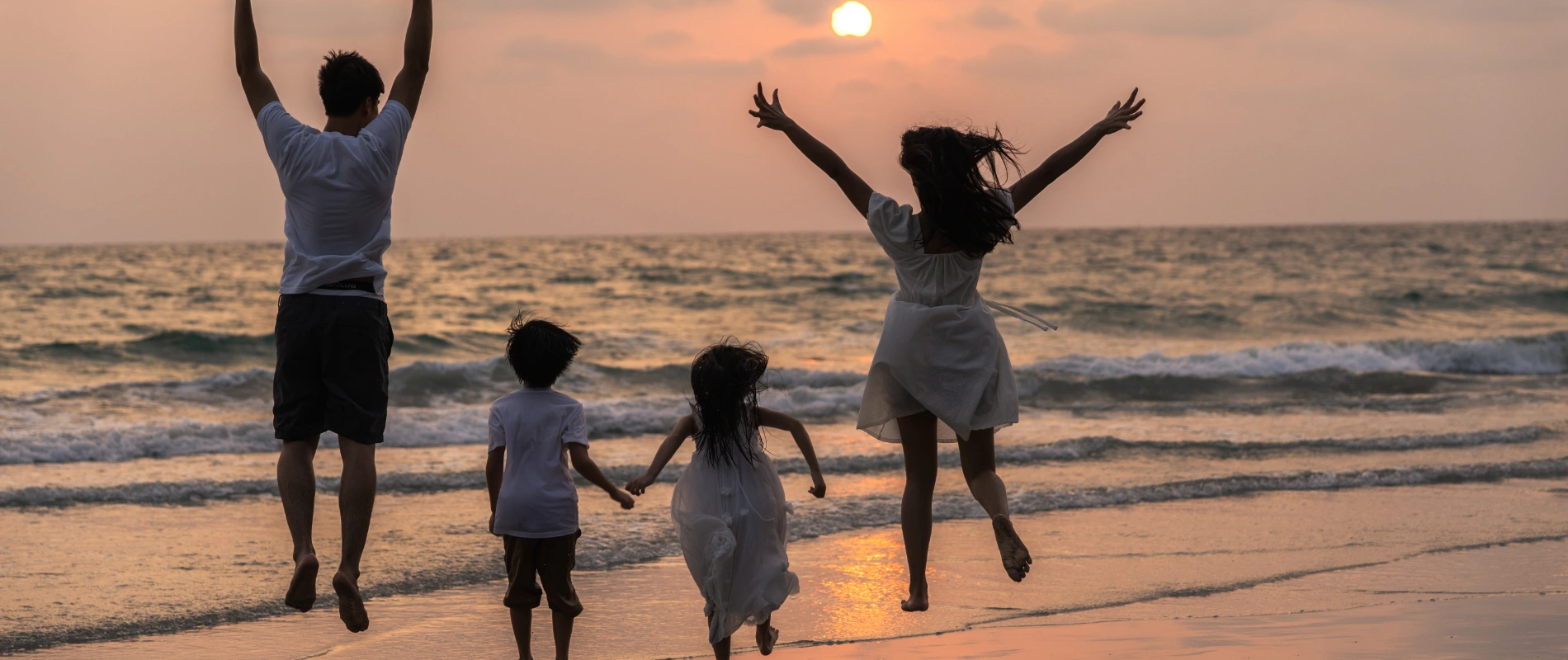 Familia saltando en la playa al atardecer.