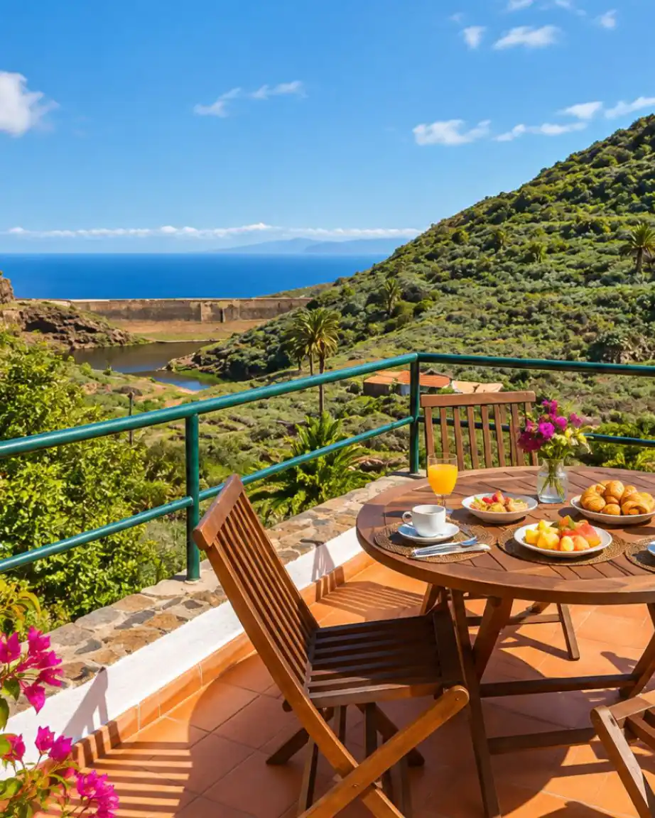Mesa con desayuno y vista al oc&eacute;ano desde una terraza junto a colinas verdes