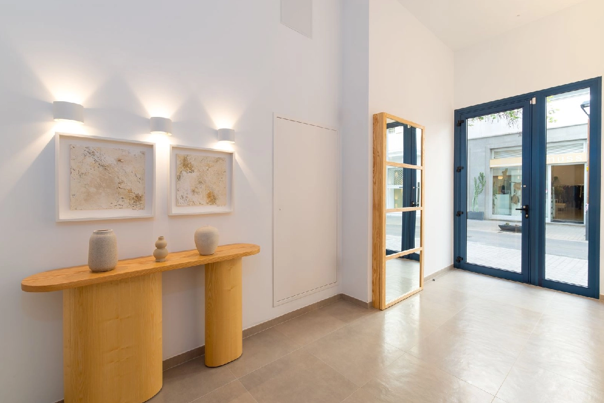 Entrada luminosa con muebles de madera y ventanas grandes.