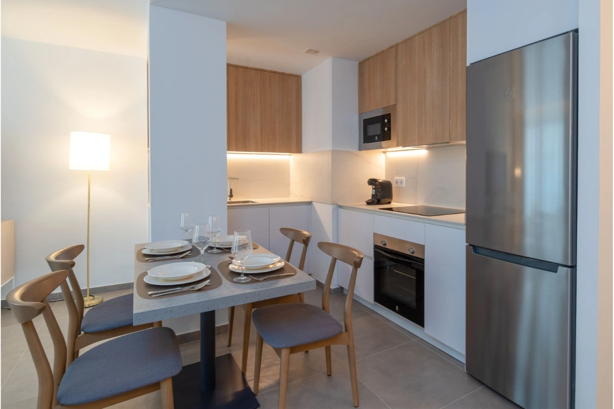 Cocina moderna con mesa puesta y luz c&aacute;lida.