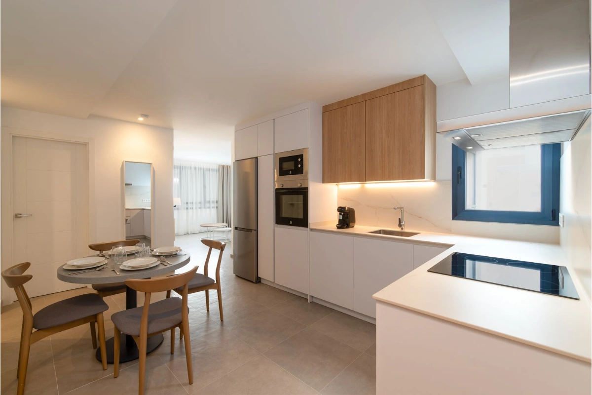 Cocina moderna con mesa redonda, sillas y electrodom&eacute;sticos integrados.