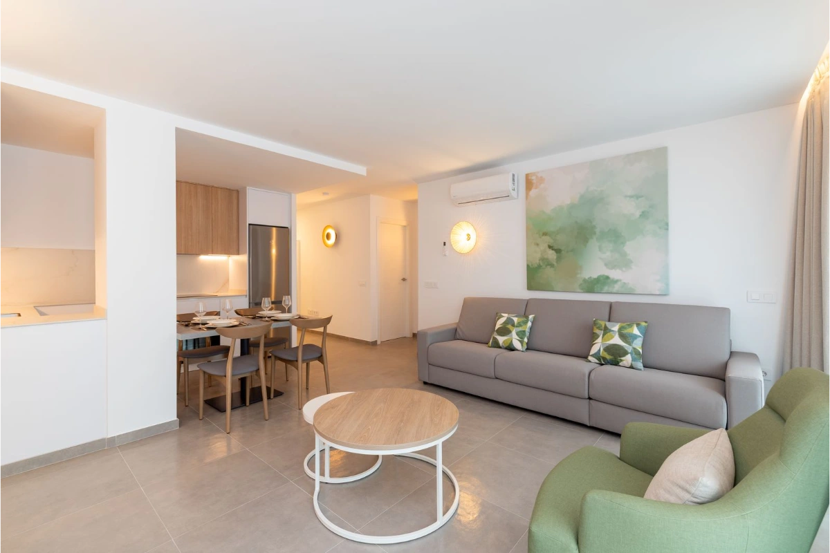 Sala moderna con cocina abierta, sof&aacute; gris y sillas verdes.