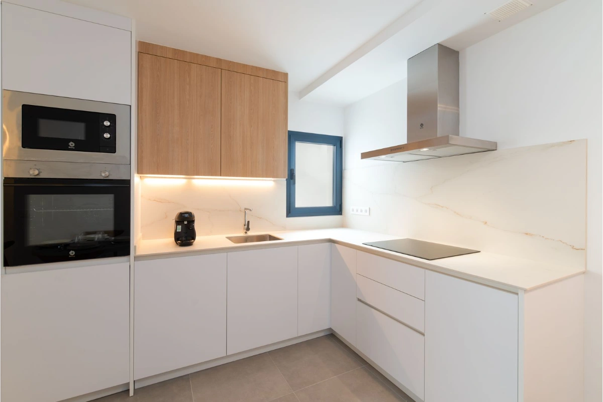 Cocina moderna con electrodom&eacute;sticos y muebles de madera y blanco.