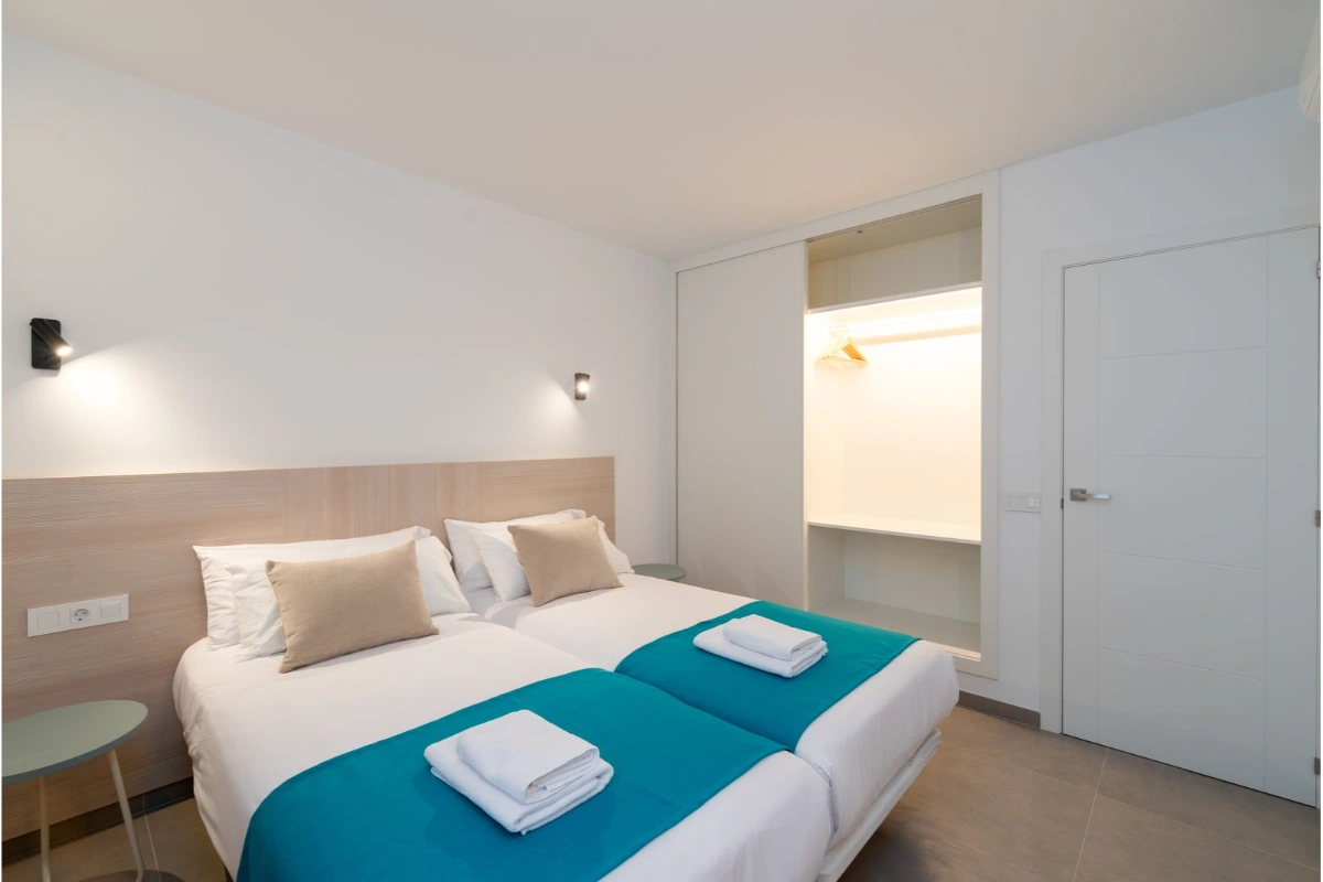 Cama doble en habitaci&oacute;n moderna con decoraci&oacute;n minimalista y armario iluminado.