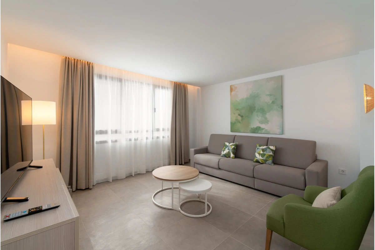 Sala moderna con sof&aacute; gris y silla verde, arte abstracto en la pared.