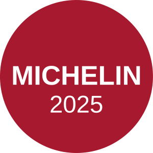 Círculo rojo con texto blanco. Sello de guía michelin 2025