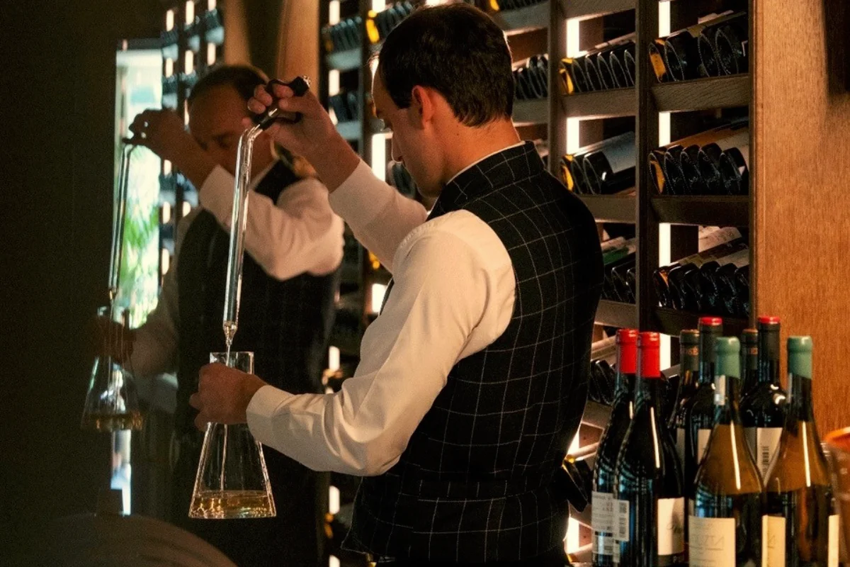 Sommelier decantando vino en una bodega moderna.