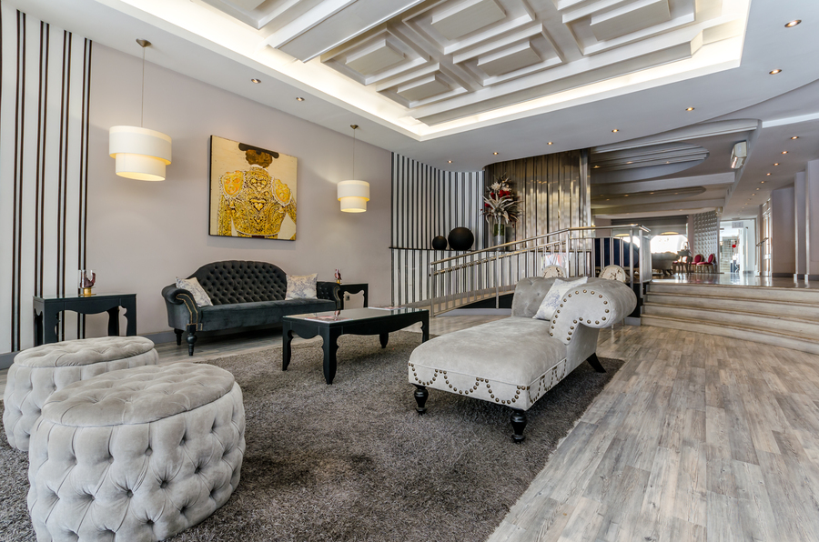 Hall de la recepción del Hotel Virgen de los Reyes con sobras en tonos grises y un cuadro de un torero en la pared
