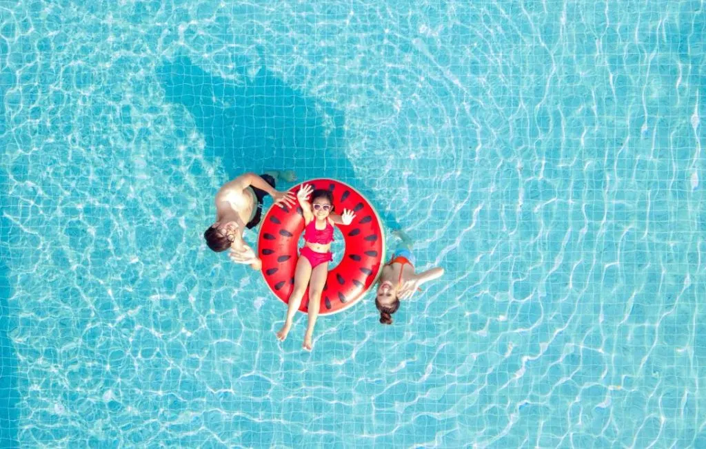 Dos mujeres flotando en una piscina con aro rojo de sandía.