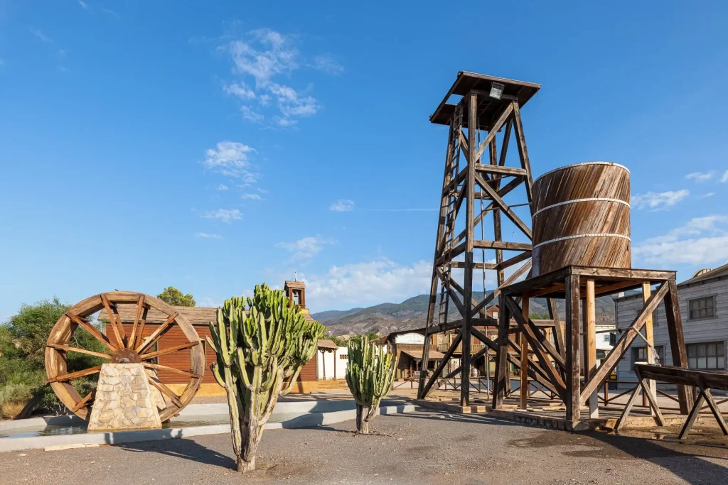 Noria de agua junto a cactus y otros decorados en el Poblado de MiniHollywood Oasys