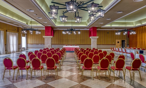 Sala de conferencias con sillas rojas alineadas y elegante iluminaci&oacute;n.
