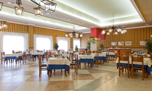 Comedor amplio con mesas montadas, l&aacute;mparas colgantes y decoraci&oacute;n elegante.