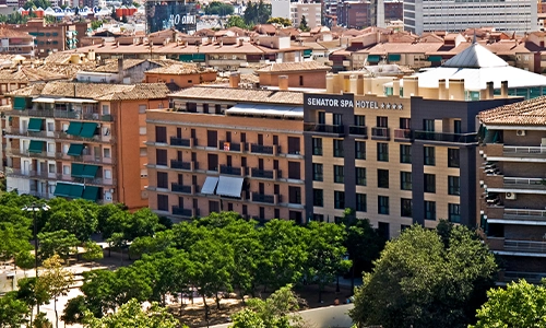 Vista a&eacute;rea de edificios y un hotel junto a un parque arbolado en la ciudad.