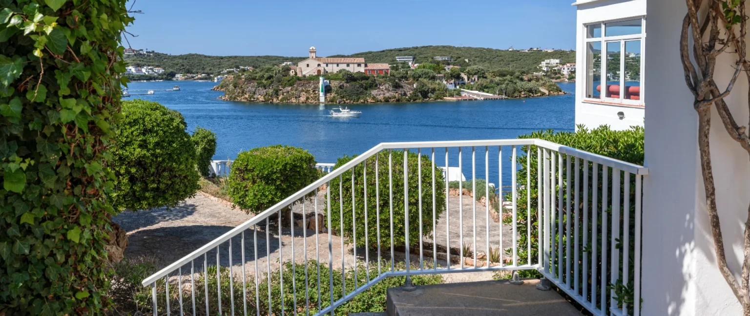 Terraza con barandilla y vista al mar y la costa con barcos y edificios