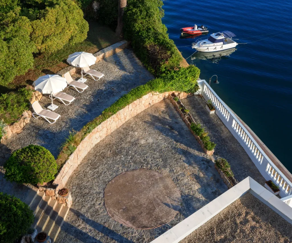 Terraza junto al mar con tumbonas, sombrillas y botes amarrados en el agua