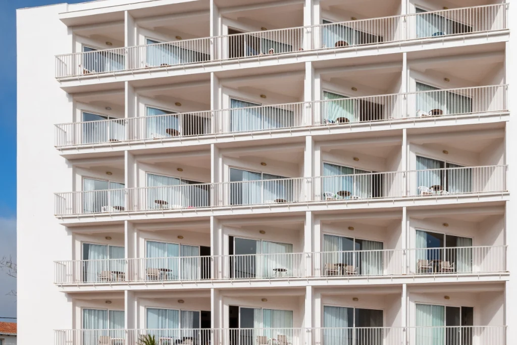 Fachada de edificio de varios pisos con balcones y barandillas de metal blanco