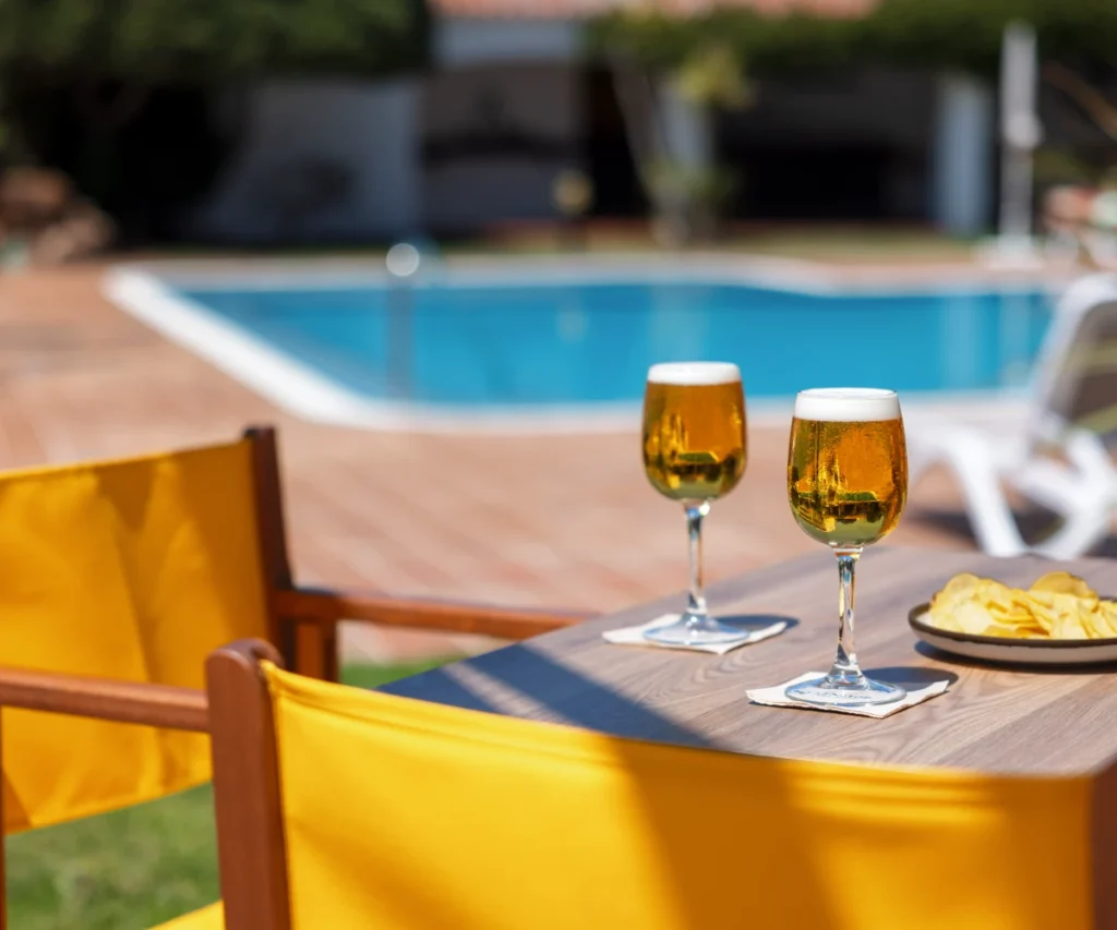 Dos copas con vino junto a una piscina en terraza al aire libre
