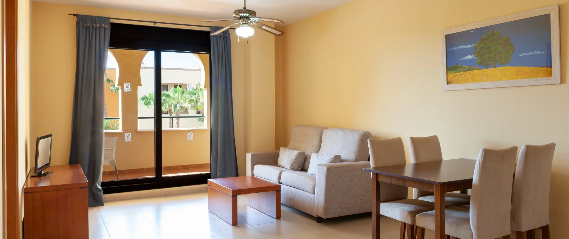 Sala de estar luminosa con sof&aacute; beige, mesa y ventana panor&aacute;mica