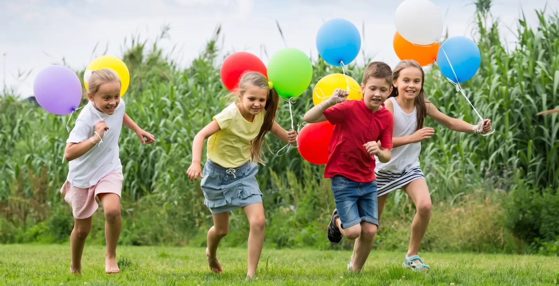 Ni&ntilde;os corriendo al aire libre con globos de colores en el jard&iacute;n