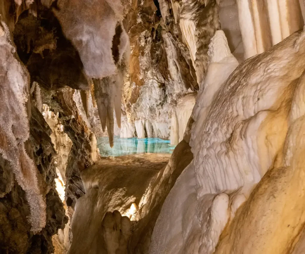 Gruta con estalactitas y un peque&ntilde;o lago azul al fondo