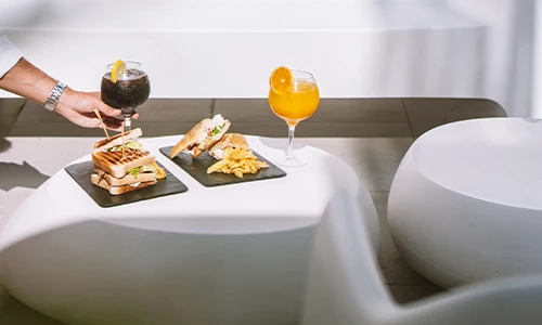 Comida en una mesa con bebidas y s&aacute;ndwiches al aire libre.