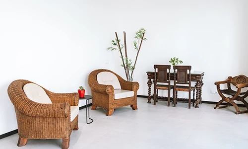 Sala con muebles de mimbre y mesa de madera oscura sobre un suelo claro.