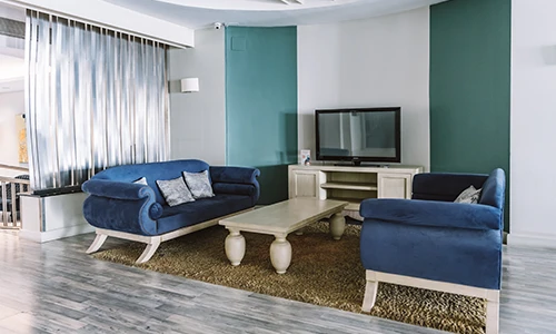 Sala moderna con sof&aacute;s azules, mesa baja y televisor sobre mueble.