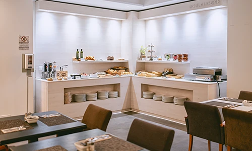 Buffet de desayuno en un restaurante con mesas y sillas en primer plano.