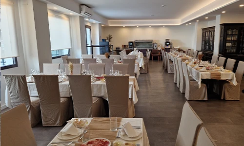 Comedor elegante con mesas cubiertas y decoradas en un ambiente iluminado.