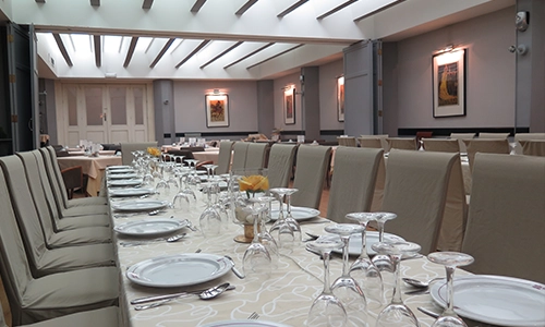 Mesa elegante preparada en un sal&oacute;n comedor con platos y copas listas.