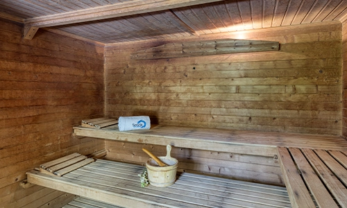 Sauna de madera con toalla y cubeta en el banco.