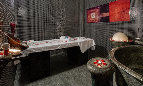 Sala de spa con camilla, velas y decoraci&oacute;n acogedora.