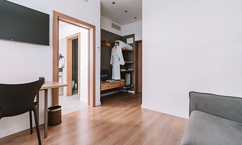 Habitaci&oacute;n moderna con suelo de madera, televisor y bata colgada.